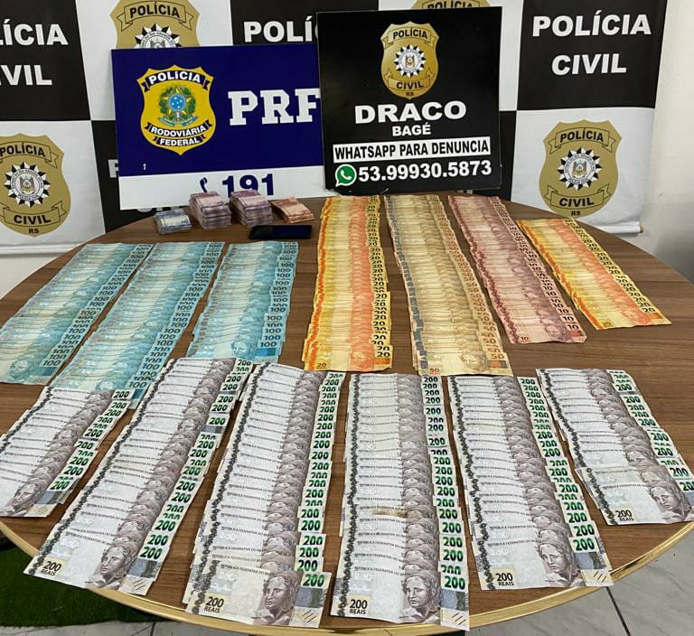 Ação policial conjunta apreende quase 38 mil reais sem procedência em Bagé O taxista que estava com o dinheiro afirmou que recebeu a quantia como pagamento por uma corrida realizada de Bagé até Santana do Livramento Na madrugada desta quinta-feira, 28, a Polícia Rodoviária Federal e a Polícia Civil (através da Operação Controle Brasil), apreenderam quase R$38 mil em espécie sem comprovação de origem. O dinheiro era transportado no porta-malas de um táxi abordado na BR 293. Durante fiscalização, policiais deram ordem de parada ao motorista de um táxi Virtus, com placas de Bagé. Em revista ao veículo, foi localizada no porta-malas, em uma sacola, a quantia de R$ 37.755,00 mil em espécie, em várias notas de todos os tipos. O homem disse inicialmente que o valor foi pago por um passageiro que ele transportou de Bagé até Santana do Livramento. Falou também que recebeu a quantia mas não havia a contabilizado. Depois, mudou a versão e disse que somente iria realizar o transporte do dinheiro. Ele foi conduzido para a Delegacia de Pronto Atendimento em Bagé e o dinheiro apreendido para comprovação de origem e investigação de possíveis crimes envolvidos.